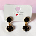 Boucles d'oreilles pendantes La boutique d'Emma dorées et émail noir avec motif smiley ludique et moderne