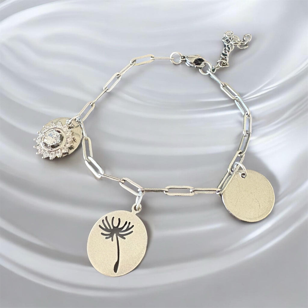 Bracelet La boutique d'Emma en métal argenté avec trois breloques : cristal, pissenlit gravé et médaillon lisse.