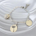 Bracelet La boutique d'Emma en métal argenté avec trois breloques : cristal, pissenlit gravé et médaillon lisse.