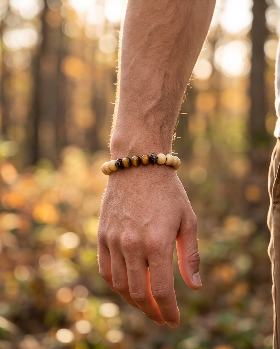 Bracelet La boutique d'Emma en perles de bois clair, bois sombre sculpté et pierre œil de tigre au poignet d'un homme