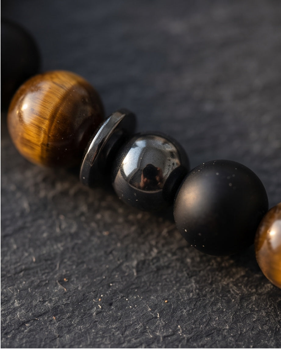 Gros plan sur un bracelet La boutique d'Emma en perles d'onyx noir mat, œil de tigre et hématite brillante
