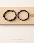 Duo de bracelets pour homme La boutique d'Emma en perles d'onyx noir mat, œil de tigre et hématite sur fond beige